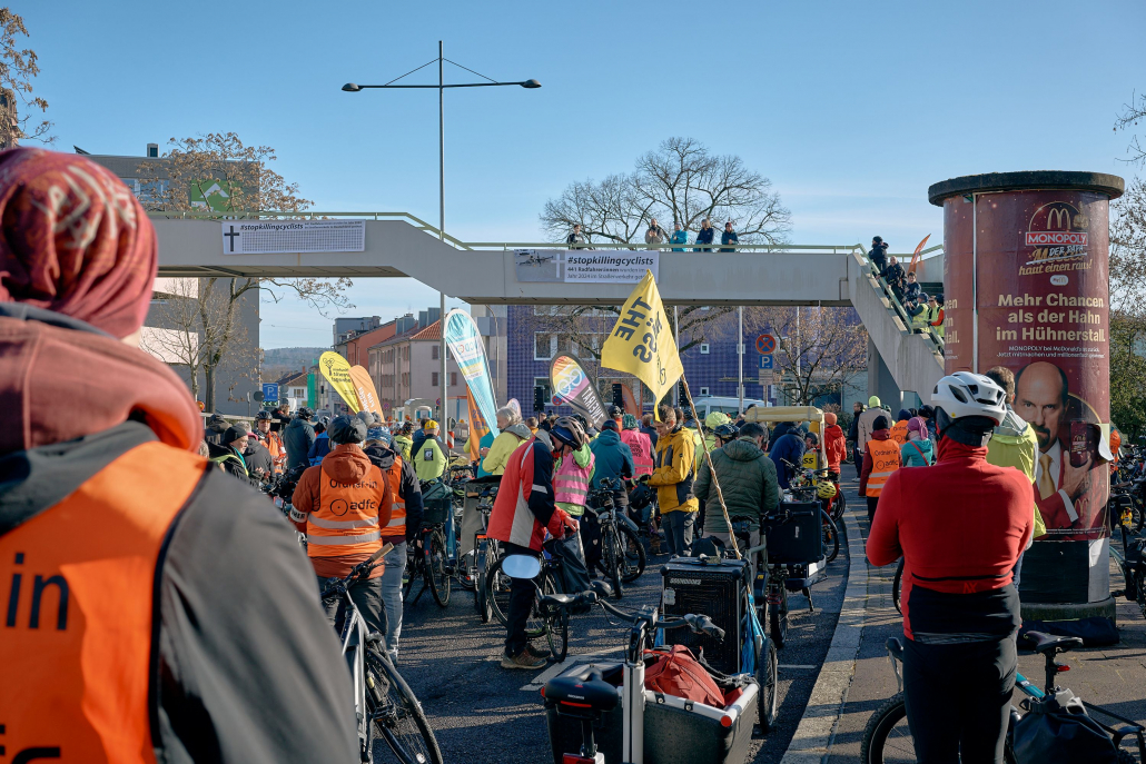 Ulrike Medger spricht bei der Auftaktkundgebung vor der Staatsanwaltschaft Pforzheim von einer Fußgängerbrücke zu den Teilnehmenden auf der Straße.